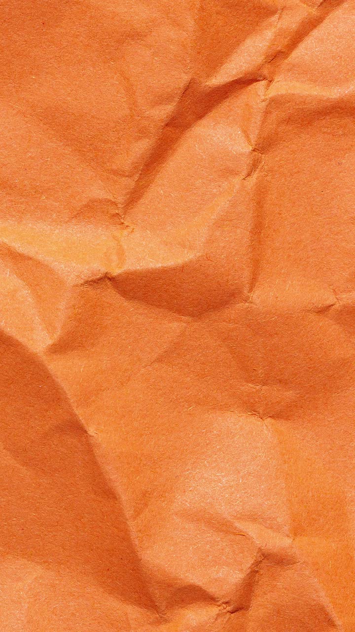 Vertical stop motion animation of crumpled orange paper, creating a looping textured background