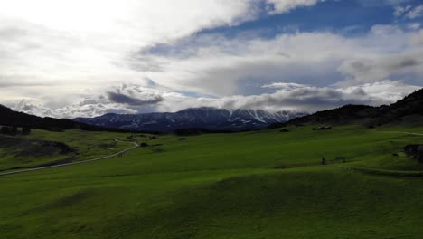 Una-Toma-De-Drones-De-Montañas-Nevadas-Contrastadas-Con-Verdes-Llanuras-Onduladas