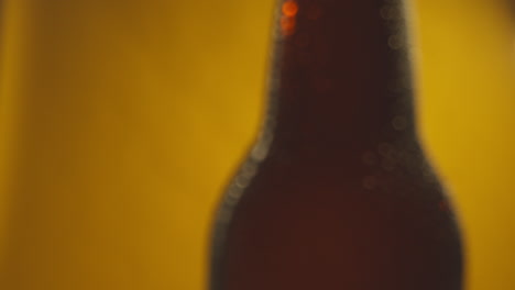 macro disparo de gotas de condensación en una botella giratoria de cerveza fría o bebidas gaseosas contra un fondo amarillo 2