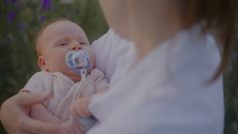 mother cradling newborn with pacifier
