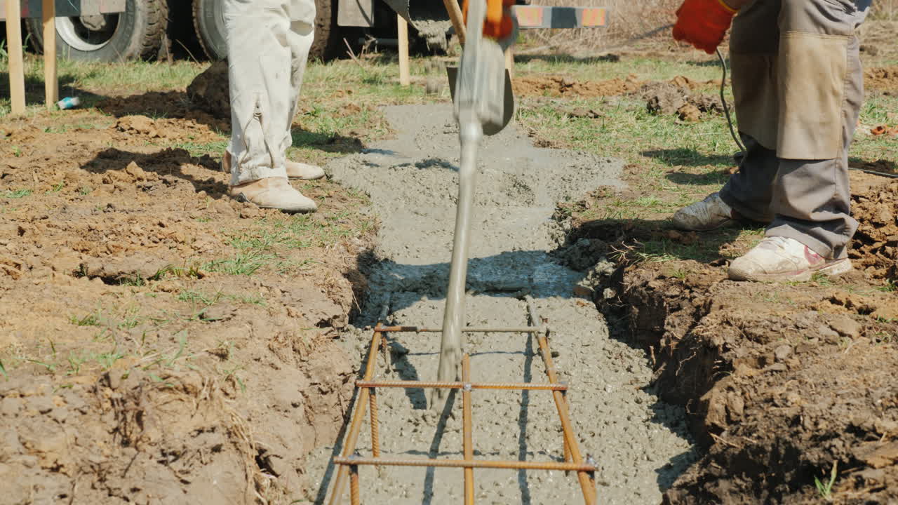 un trabajador con un vibrador y una pala saca hormigón de la hormigonera trabajo manual pesado en la construcción