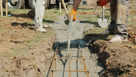 a worker with a vibrator and shovel takes concrete from the mixer heavy manual labor at the construc