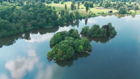 mirror reflections over calm waters of trentham lake in england