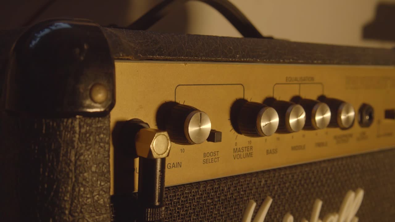 Close-up of a hand adjusting the knobs on a vintage guitar amplifier