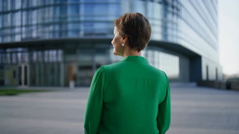 woman in green shirt looking towards modern office building