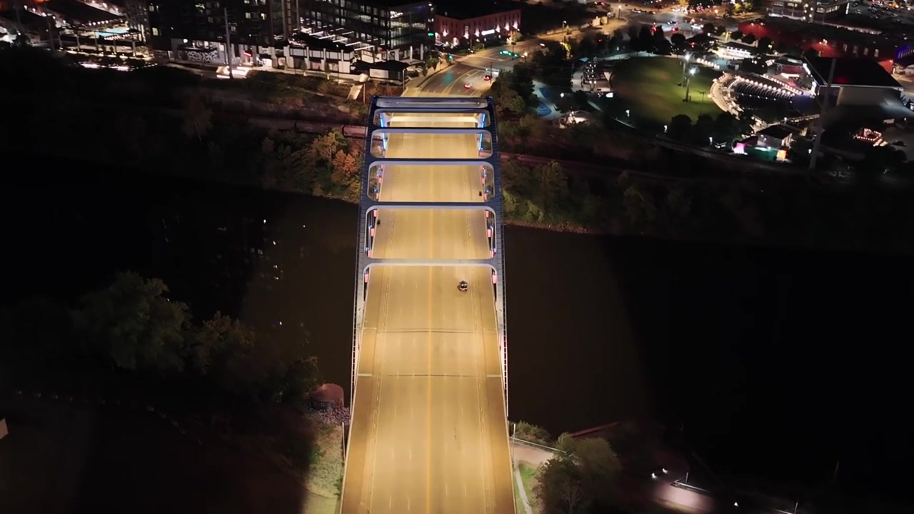 Aerial drone shot capturing Nashville's driving bridge on Korean Boulevard, with city lights in the background and the Cumberland River running underneath