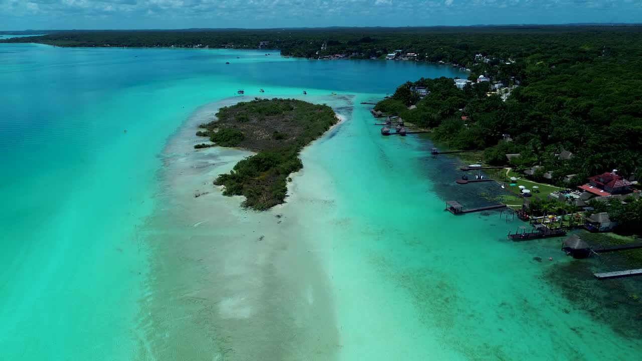 Drone aerial landscape of island in lagoon lake and cenote with jetty boardwalk wharf with resort huts hotels Bacalar Mexico Quintana Roo travel holidays tourism