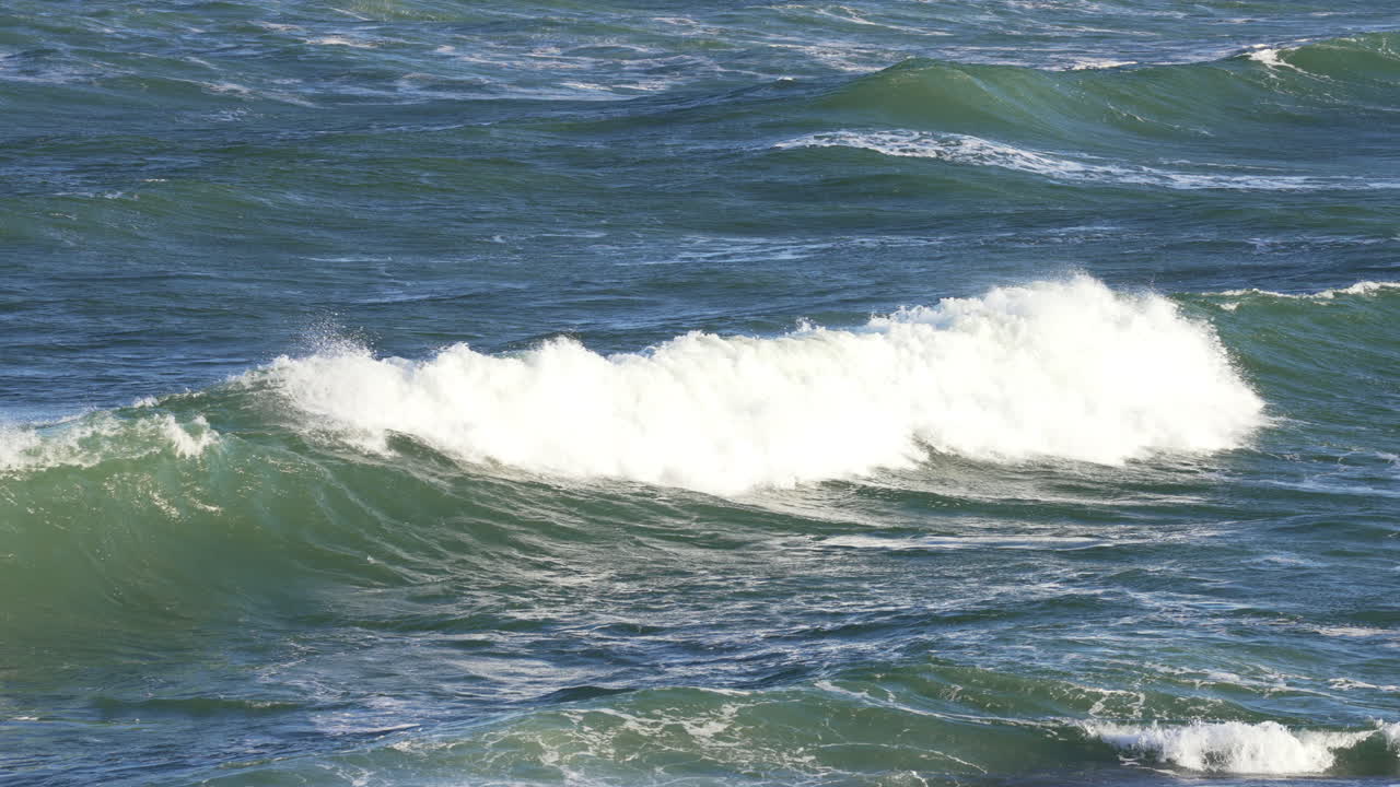 4k cámara lenta de las olas del océano rompiendo creando un lavado blanco en el mar azul