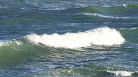 4k cámara lenta de las olas del océano rompiendo creando un lavado blanco en el mar azul