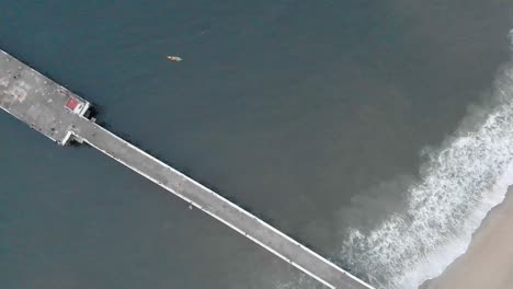 4k aerial top down dolly moving forward shot of a shipping port pier on a sunrise with monsoon clouds covered near rock beach shot with a drone, pondicherry, india