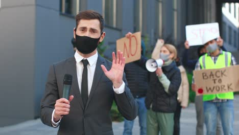 caucasian journalist or correspondent wearing protective mask giving interview in a protest against covid 19