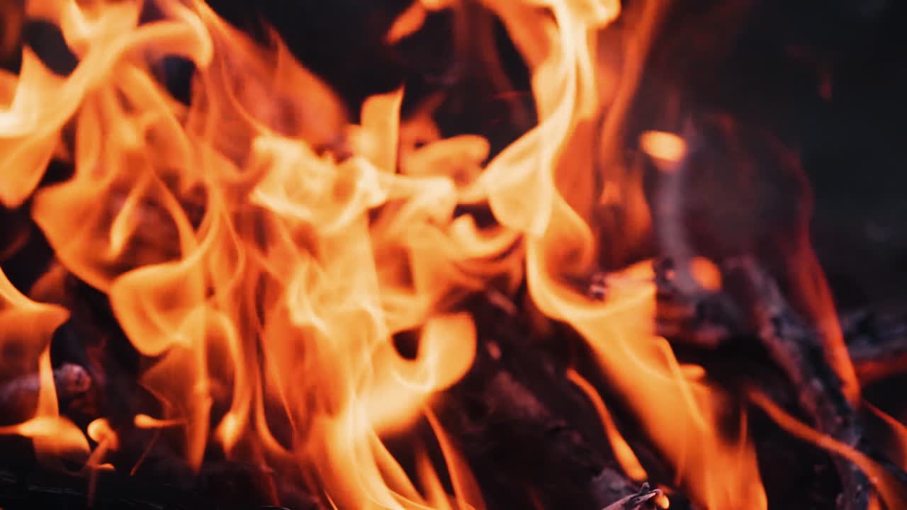 Fuoco che brucia. Falò. Primo piano di fiamme che bruciano su sfondo nero, rallentatore.