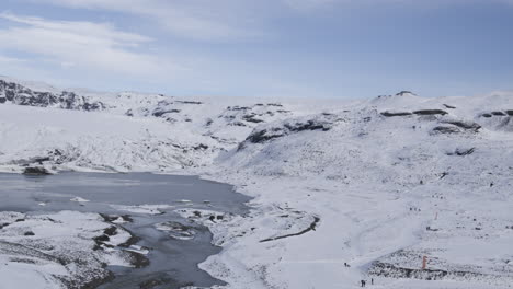 Aerial-revealing-shot-showing-a-group-of-explorers-within-a-frozen-Icelandic-mountain