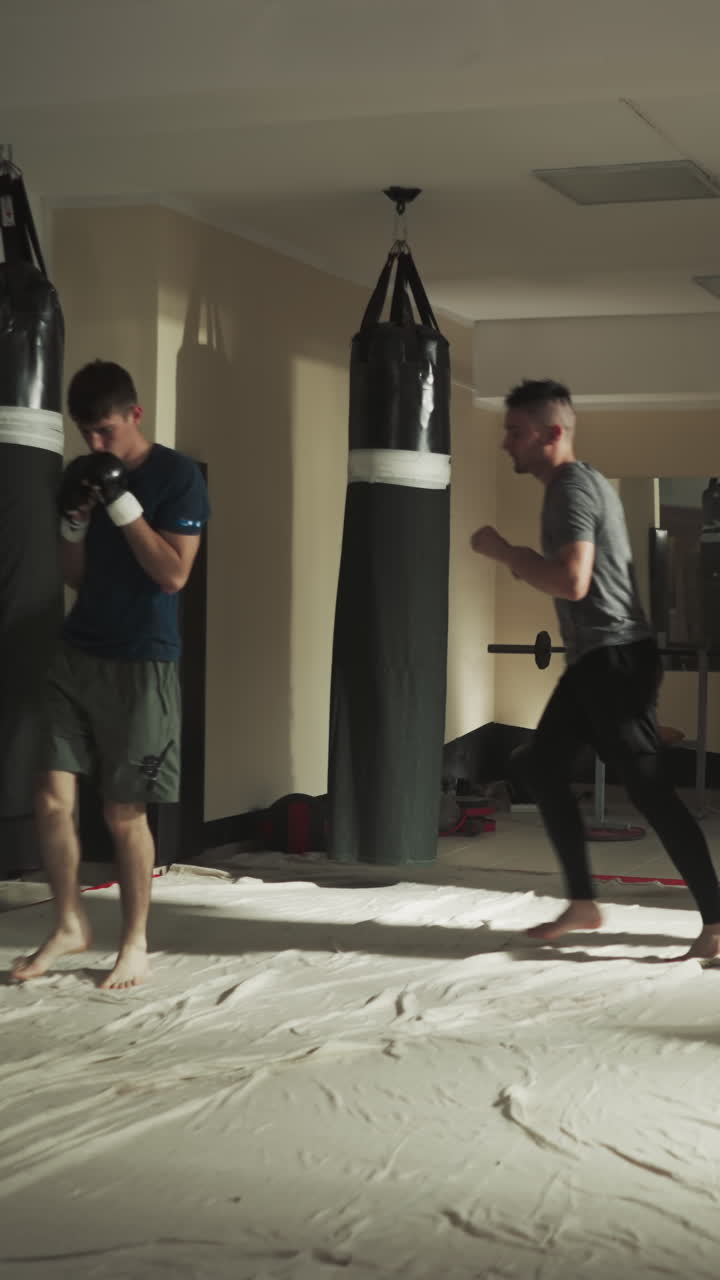 전투기들은 공중에서 점프하고 치며 스트라이크를 모방합니다. 체육관에서 훈련합니다. 스포츠맨 그룹은 무술 클럽에서 함께 신체 운동을 합니다. 느린 동작. 전투 선수.