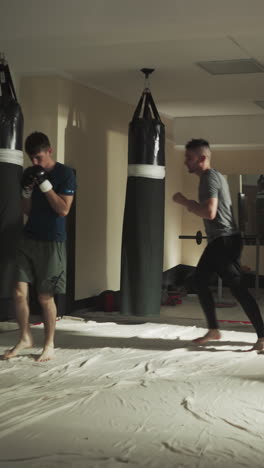 los luchadores saltan y golpean el aire imitando los golpes entrenando en el gimnasio. grupo de deportistas hace ejercicios físicos juntos en el club de artes marciales en cámara lenta. atleta de combate