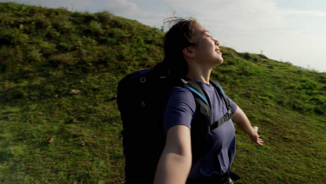 una joven mujer morena gira en el cálido sol en la cima de una montaña sonriendo después de ir de mochila a la cima