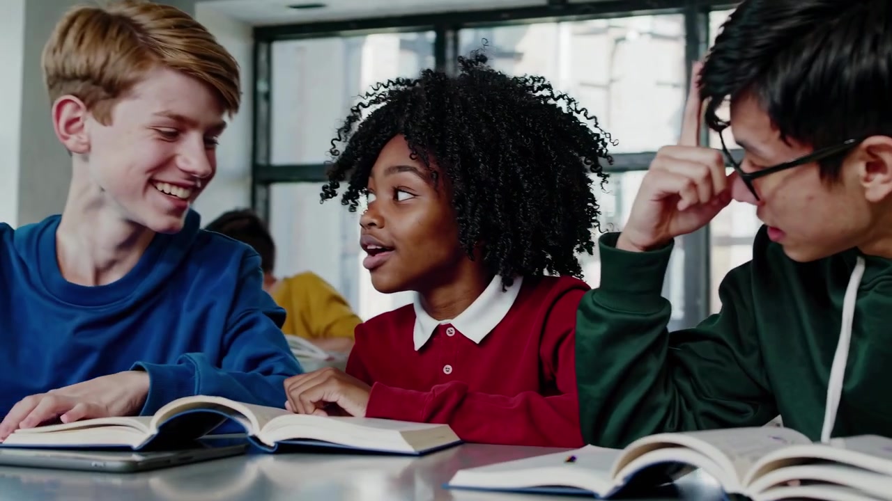 Diverse Students Collaborating with Tablet and Books in Classroom