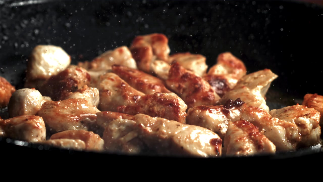 Primo piano di pezzi di pollo che friggono in una padella calda