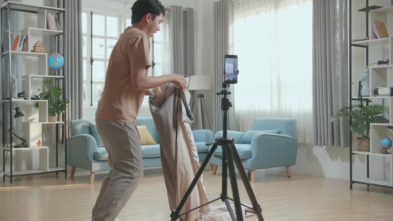Man Demonstrating a Photography Setup in Home Studio Using a Tripod