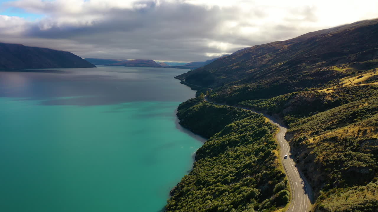 Aerial drone view of a scenic road along a picturesque turquoise lake on New Zealand's South Island