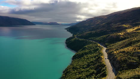 aerial drone view of a scenic road along a picturesque turquoise lake on new zealand's south island