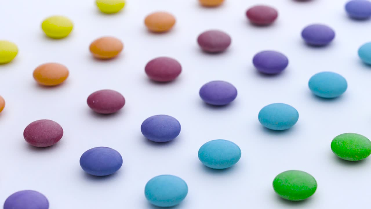 las filas de dulces redondas coloridas se mueven diagonalmente sobre el fondo blanco.