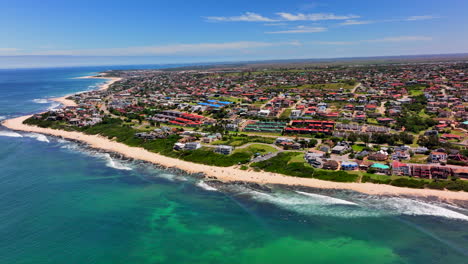 Südafrika-Jbay-Jeffreys-Bay-Luftaufnahme-Drohne-Stadt-Häuser-Gebäude-Atemberaubendster-Weißer-Sandstrand-Epische-Brandung-Welle-Aqua-Blau-Zerklüftetes-Riff-Küste-Tagsüber-WSL-Corona-Offen-Supers-Boneyard-Sommer-Oben-Kreis