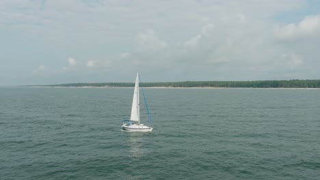 Aerial-establishing-view-of-a-white-sailboat-in-the-calm-Batltic-sea,-white-sailing-yacht-in-the-middle-of-the-boundless-sea,-sunny-summer-day,-wide-orbiting-done-shot