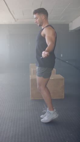 vertical video: jumping rope, man exercising in gym wearing athletic wear and sneakers
