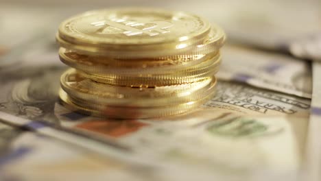 pile of golden bitcoin coins rotating above usd dollar bills american cash money close up studio shot