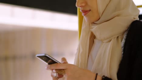 animation of asian woman in hijab using smartphone over cityscape