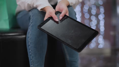 cerca de las manos sosteniendo la tableta con uñas pulidas, balanceándola suavemente mientras la pantalla refleja luces suaves, con un fondo sutil y borroso de iluminación decorativa