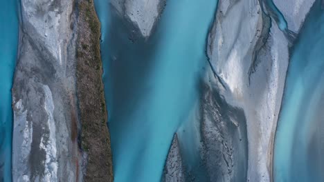 top down drone shot of blue glacial braided river weaving through landscape like abstract art, godley river, new zealand
