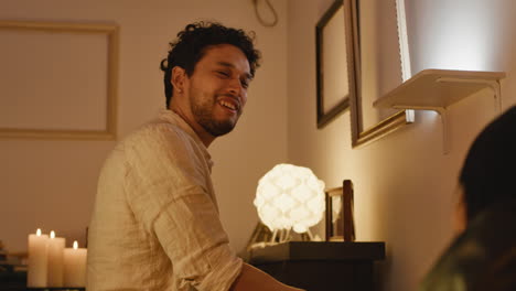 man playing piano with candles and lamp in room