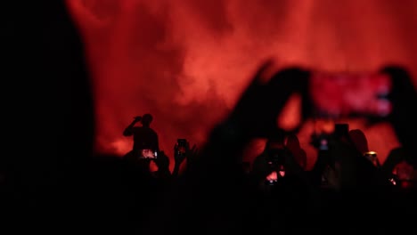 nighttime music concerts: fans record videos of singer on stage, hold smartphones and dance with lights