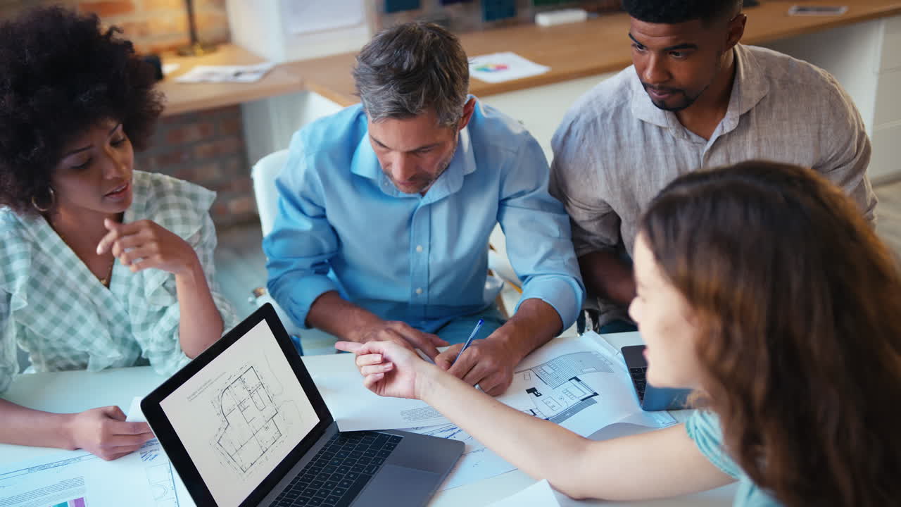 vista elevada del equipo de negocios masculino y femenino con reunión de computadora portátil en una oficina moderna