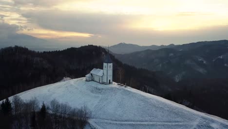 Vista-De-La-Iglesia-Jamnik-En-Un-Paisaje-Invernal-Con-Un-Colorido-Amanecer-En-Kranj,-Eslovenia