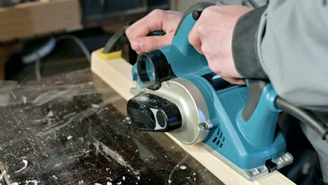 close-up of a carpenter's hand working with an electric plane in a home workshop