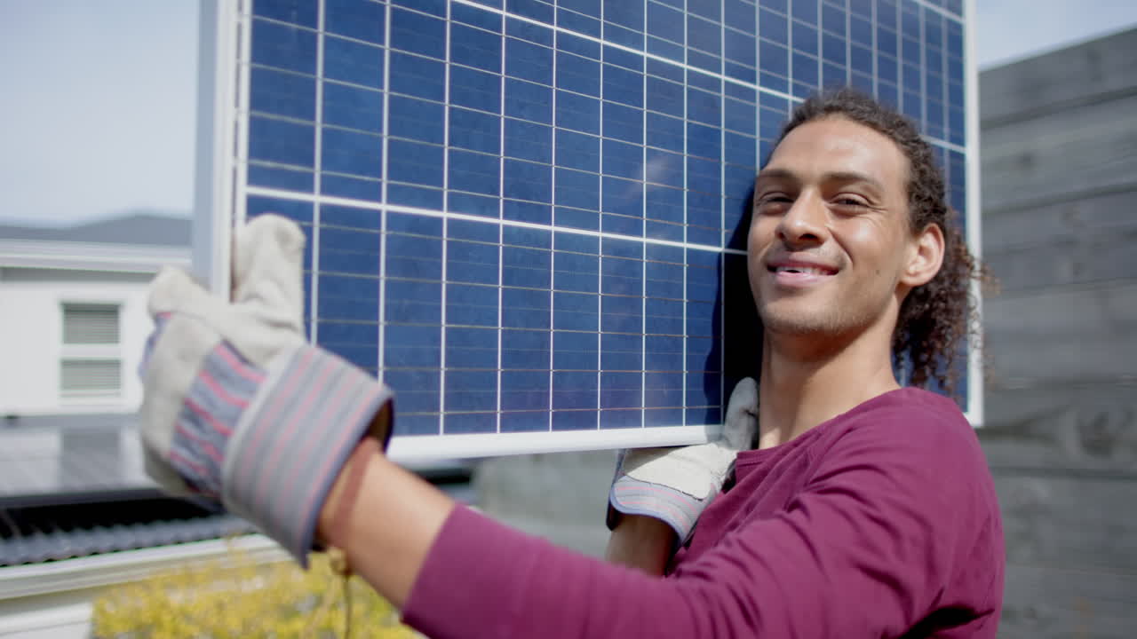retrato de un hombre feliz de dos razas con guantes llevando un panel solar en el jardín, cámara lenta