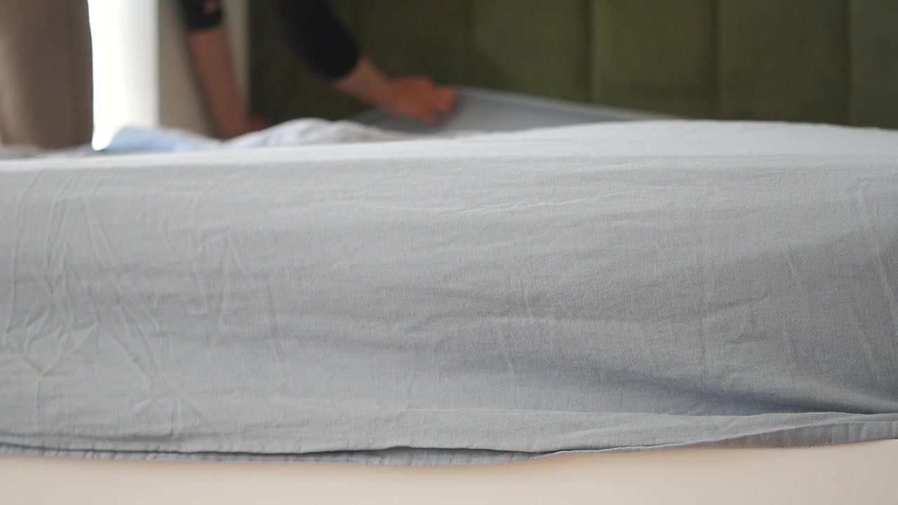 Person Making Bed and Smoothing Light Blue Sheet