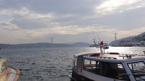 view of bosphorus bridge in fog in istanbul, turkey with boat floating on foreground