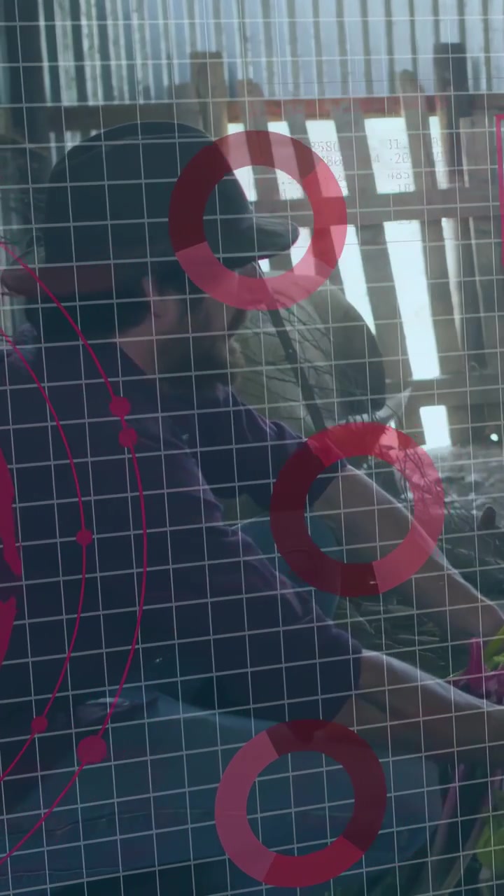 Vertikal video: Mand håndterer telefon ved vindue med gennemsigtigt gitter og magenta overlay, der afslører teknologisk brugerflade.