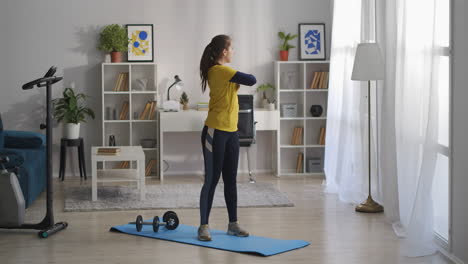 teen-girl-is-doing-physical-exercises-at-morning-in-living-room-of-modern-apartment-at-weekends-stretching-hands-and-back-muscles