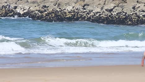 hombre camina por la playa con una cámara en la mano, fuera de foco