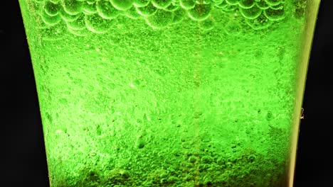 macro shot of a glass with many green bubbles floating and dripping in water