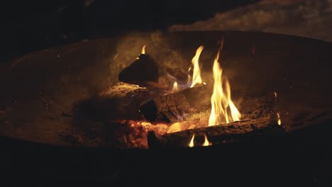 Burning-flame-in-round-metal-bowl-during-night-time-in-cold-winter-forest