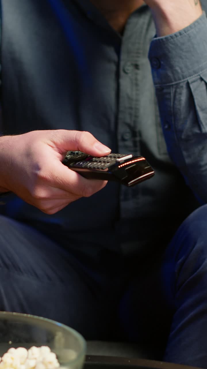 Vertical video Close up of man on couch using remote control