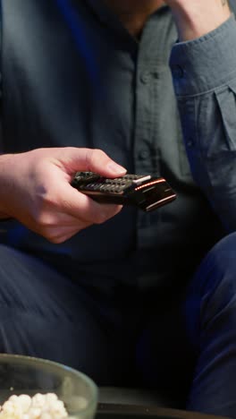vertical video close up of man on couch using remote control