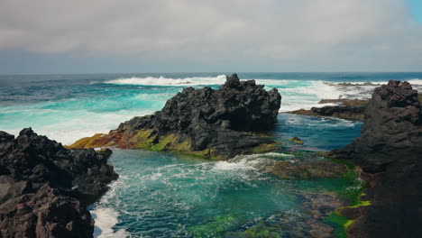 Slow-motion-shot-of-rough-ocean-waves-crushing-against-the-volcanic-rocky-coastline
