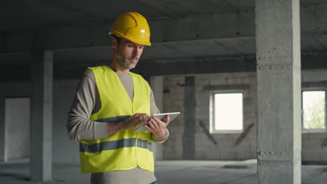 caucasian engineer walking and browsing digital tablet on construction site.